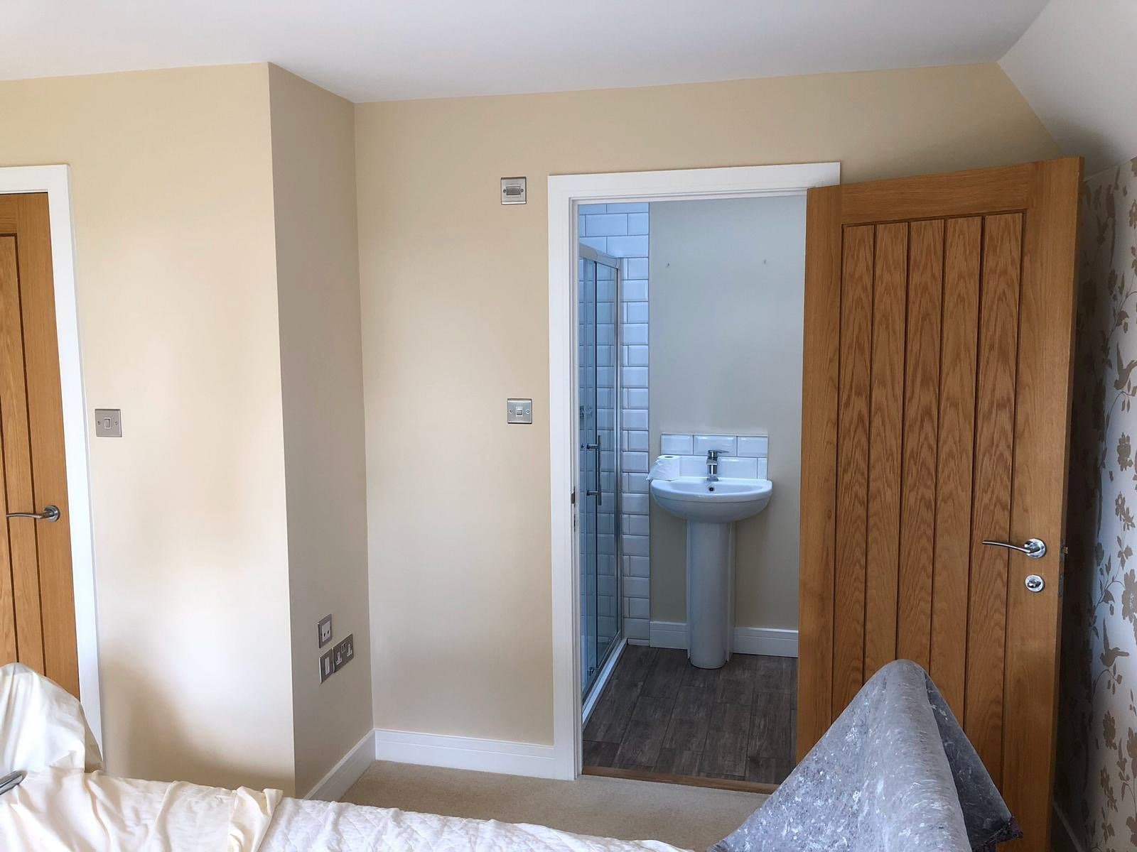 Bedroom with en-suite bathroom and wooden door.