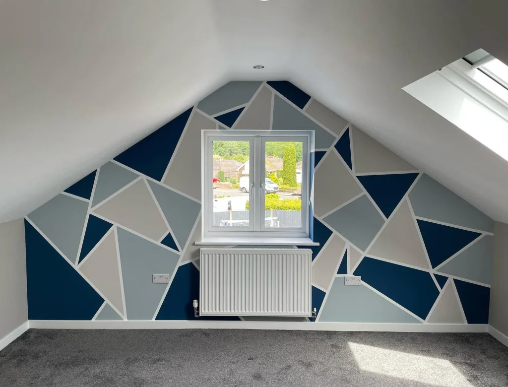 Attic room with geometric feature wall and window.