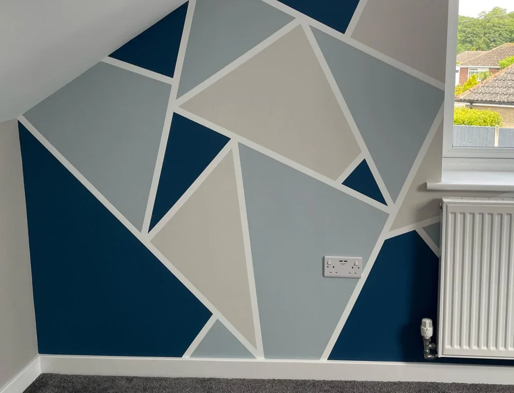 Geometric pattern wall with blue, grey, cream triangles.
