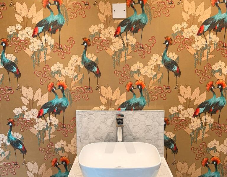 Bathroom sink against colourful crane patterned wallpaper
