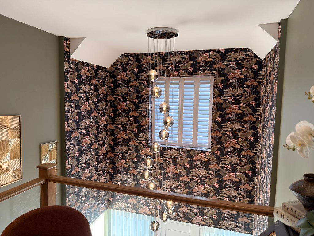 A stairwell hung with dramatic dark botanical wallpaper