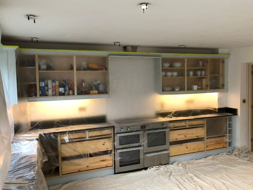 Before: kitchen cabinets stripped back and masked for spraying