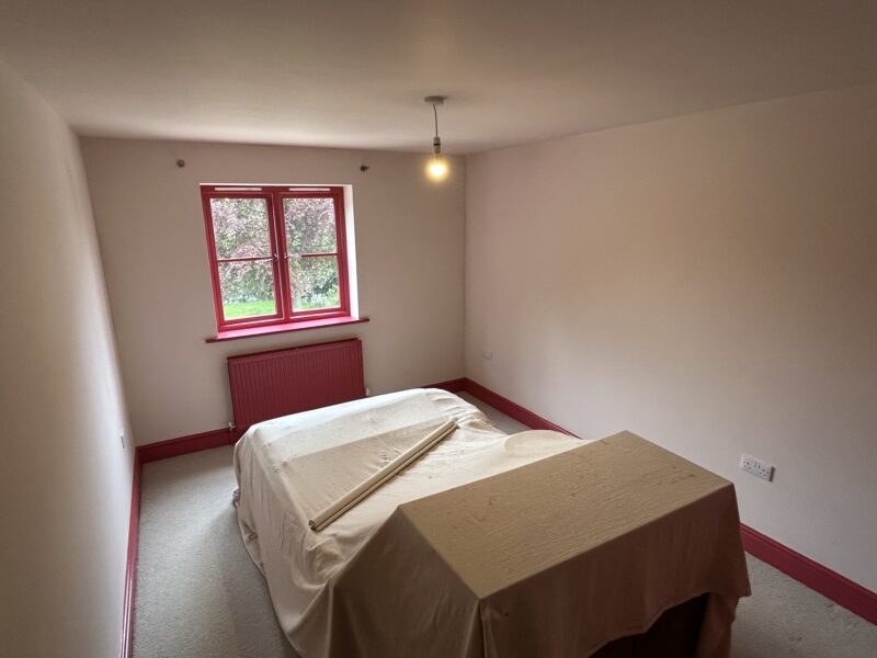 Small bedroom with red window frame and radiator