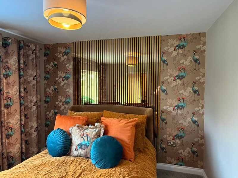 Stylish bedroom with bird wallpaper and mustard bedding