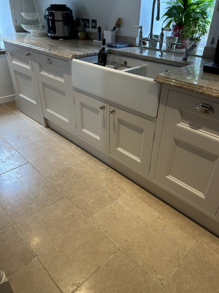 Cream kitchen cabinets with farmhouse sink and stone floor