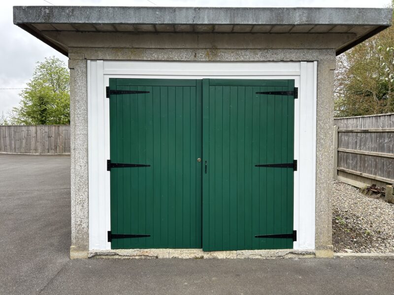 Green wooden double garage doors with black hinges