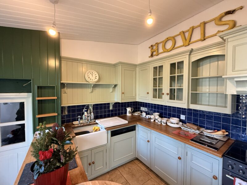 Traditional kitchen with sage cabinets and blue tiles
